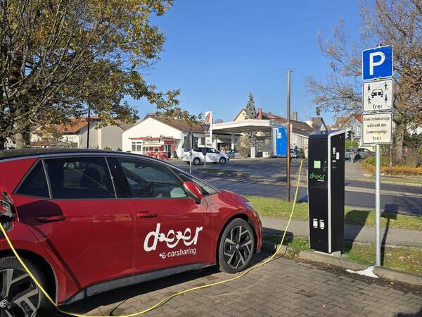 Ein rotes Auto auf einem Parkplatz an einer E-Ladesäule.
